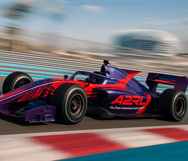 A sleek autonomous A2RL Formula-style race car speeds around Yas Marina Circuit, showcasing advanced AI technology with vibrant red and purple design.