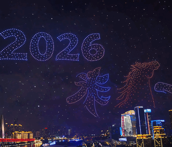 Vibrant night skyline beneath a massive drone light show forming 2026 with colourful patterns above a river city celebration fireworks
