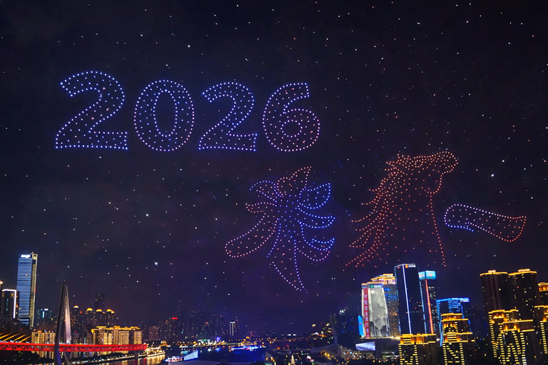 Vibrant night skyline beneath a massive drone light show forming 2026 with colourful patterns above a river city celebration fireworks