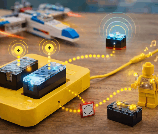 Lego Smart Bricks glowing on a table, wirelessly interacting with a minifigure, smart tag and spaceship during playful hands on building.